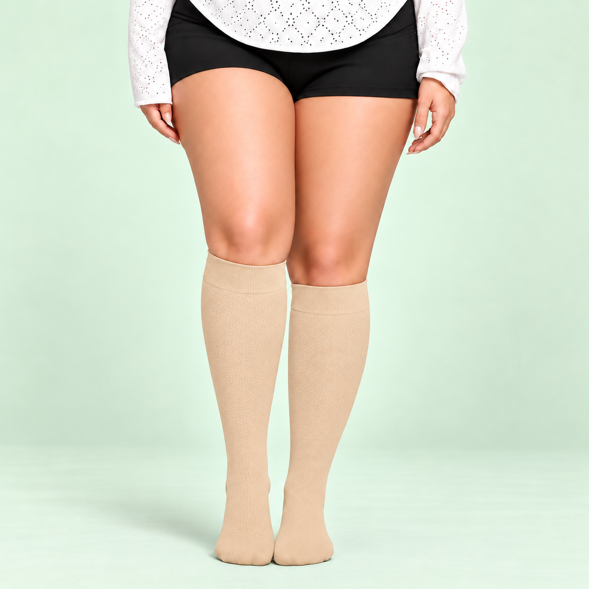 Skin bamboo compression socks, standing front view on a pale sage background