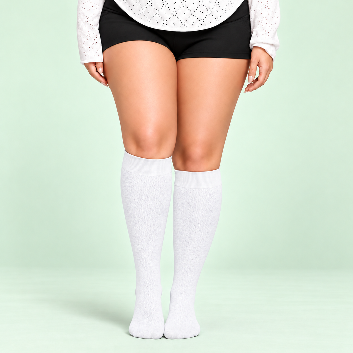 White bamboo compression socks, standing front view on a pale sage background
